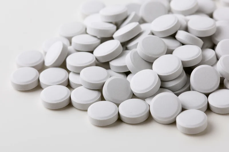 Pile of small white round tablets scattered on a plain surface