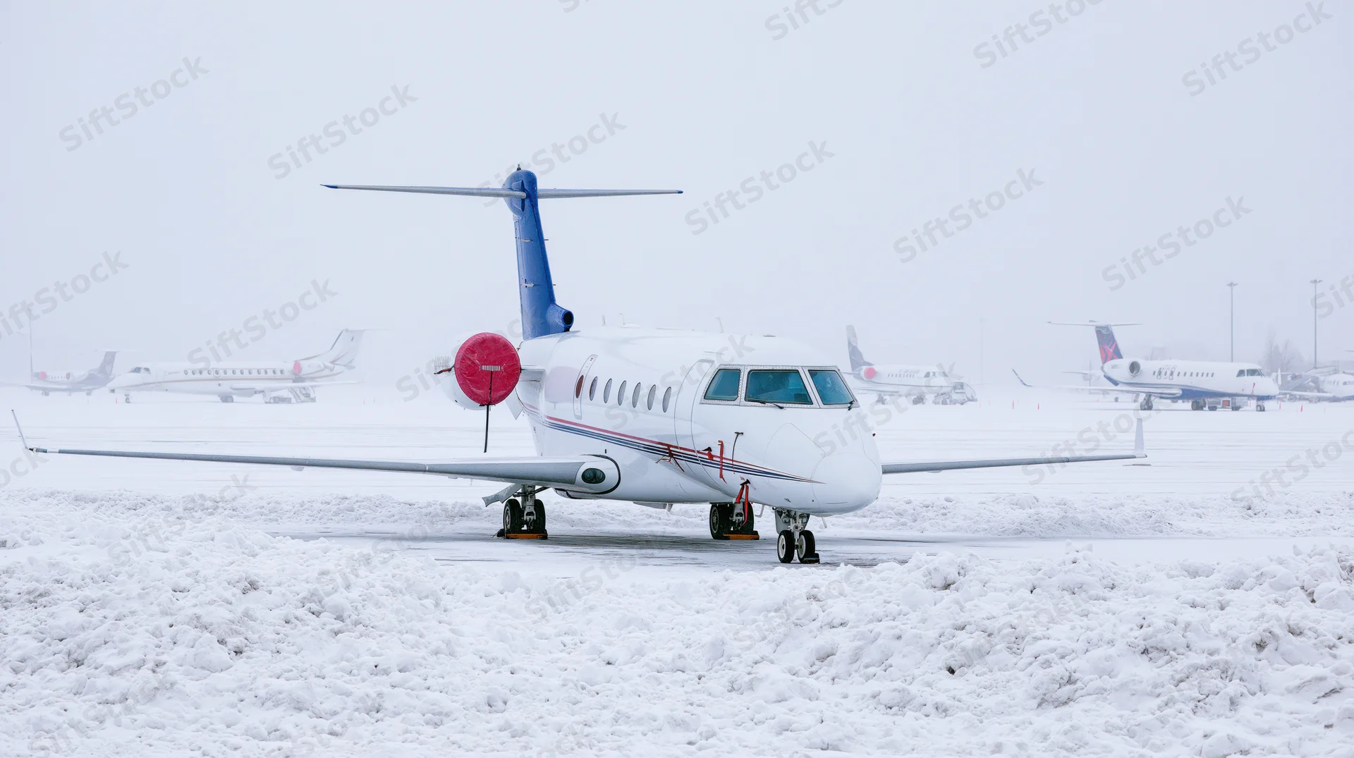 Private business jet parked on snow-covered airport tarmac