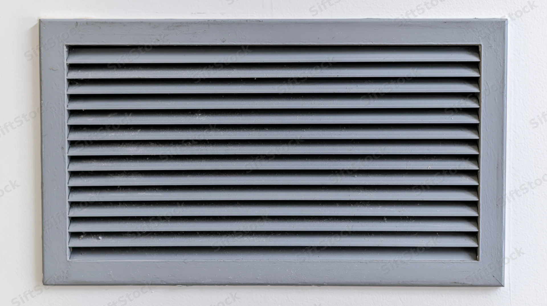 Rectangular metal vent grille with horizontal louvers mounted on a white wall