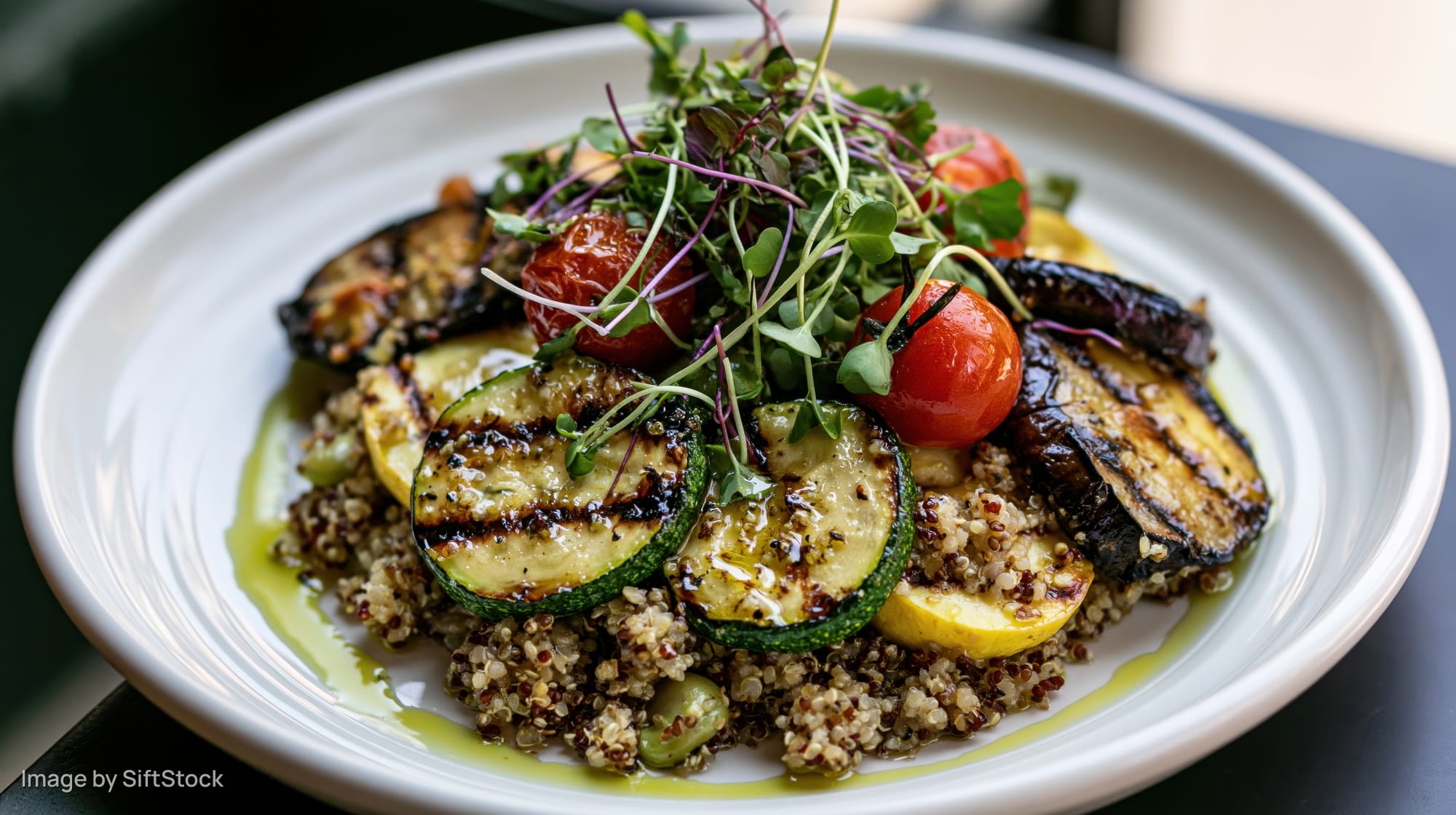 Grilled vegetable and quinoa salad served on a white ceramic plate