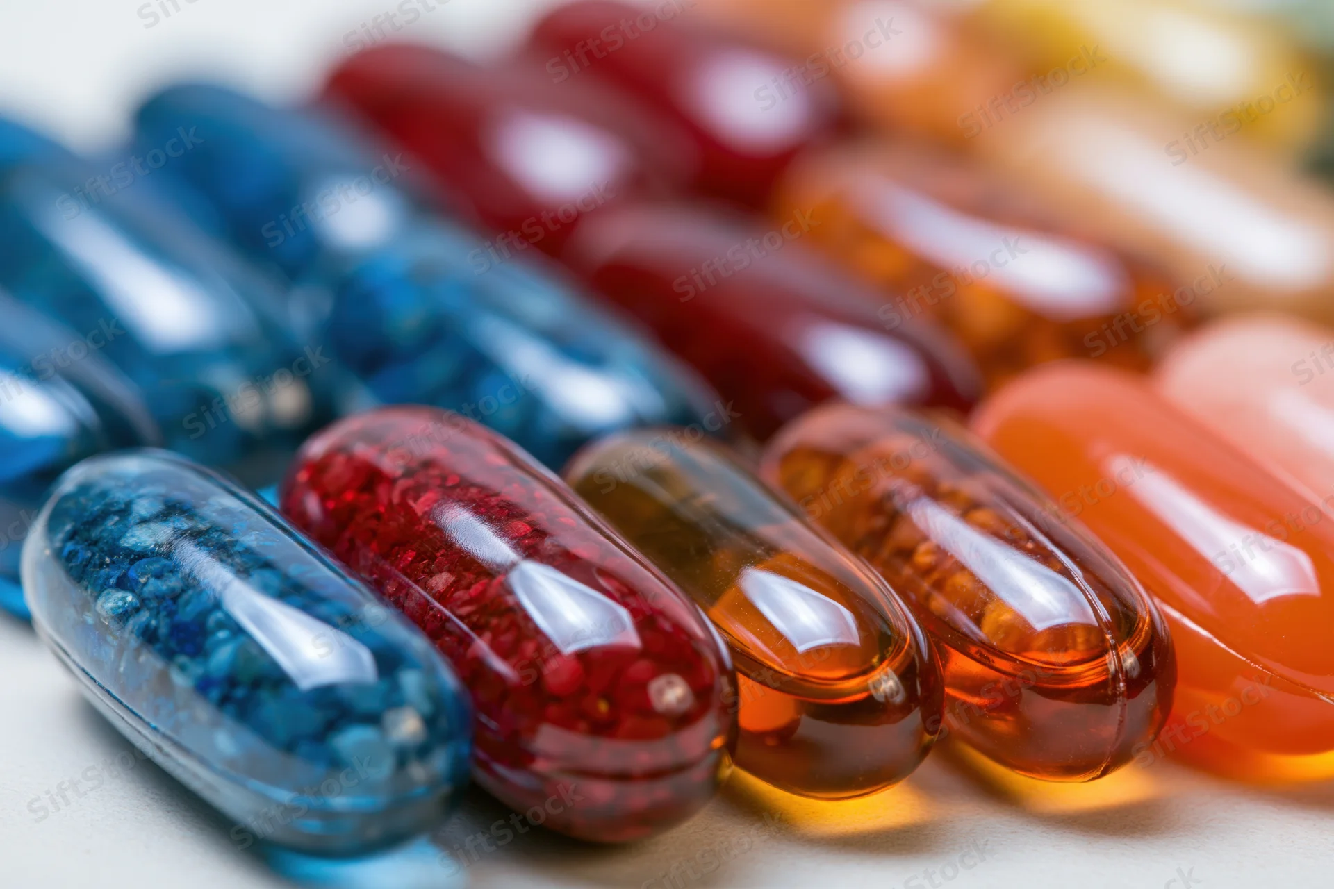 Rows of colorful transparent gel capsules arranged in neat lines on a light surface
