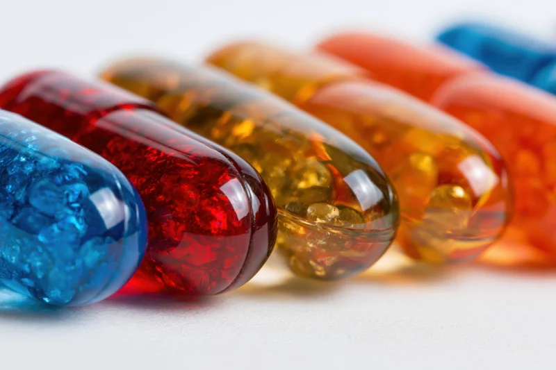 Rows of colorful gel capsules arranged in a line on a white surface