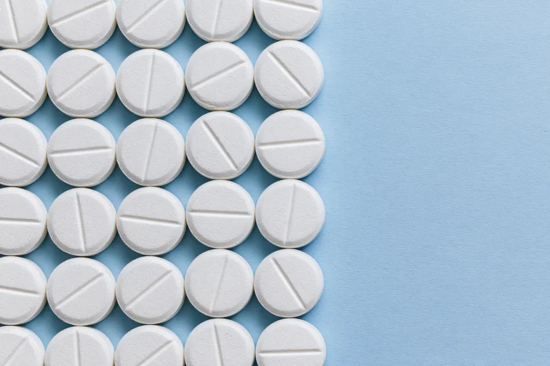 White scored tablets arranged in a grid on a blue surface with copyspace on the right