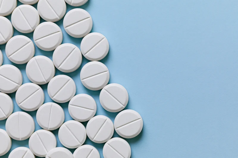 White scored tablets arranged in a grid on a blue surface with copyspace