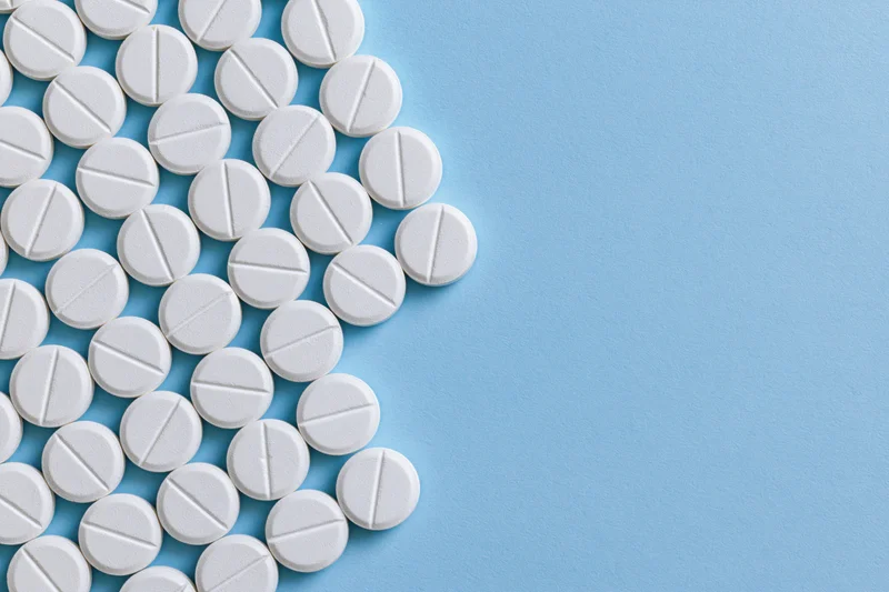 White scored tablets arranged in a grid on a blue surface with copyspace