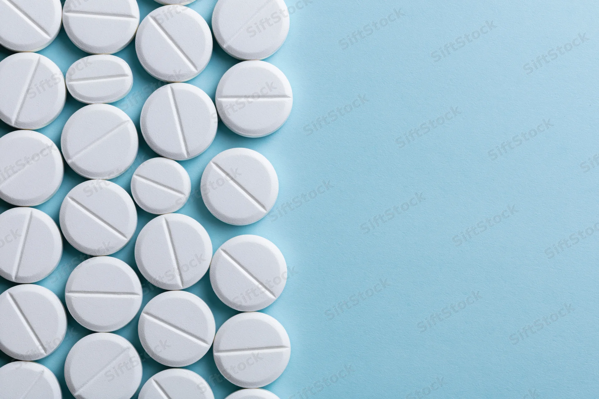 White scored tablets arranged in a grid on a blue surface with copyspace on the right