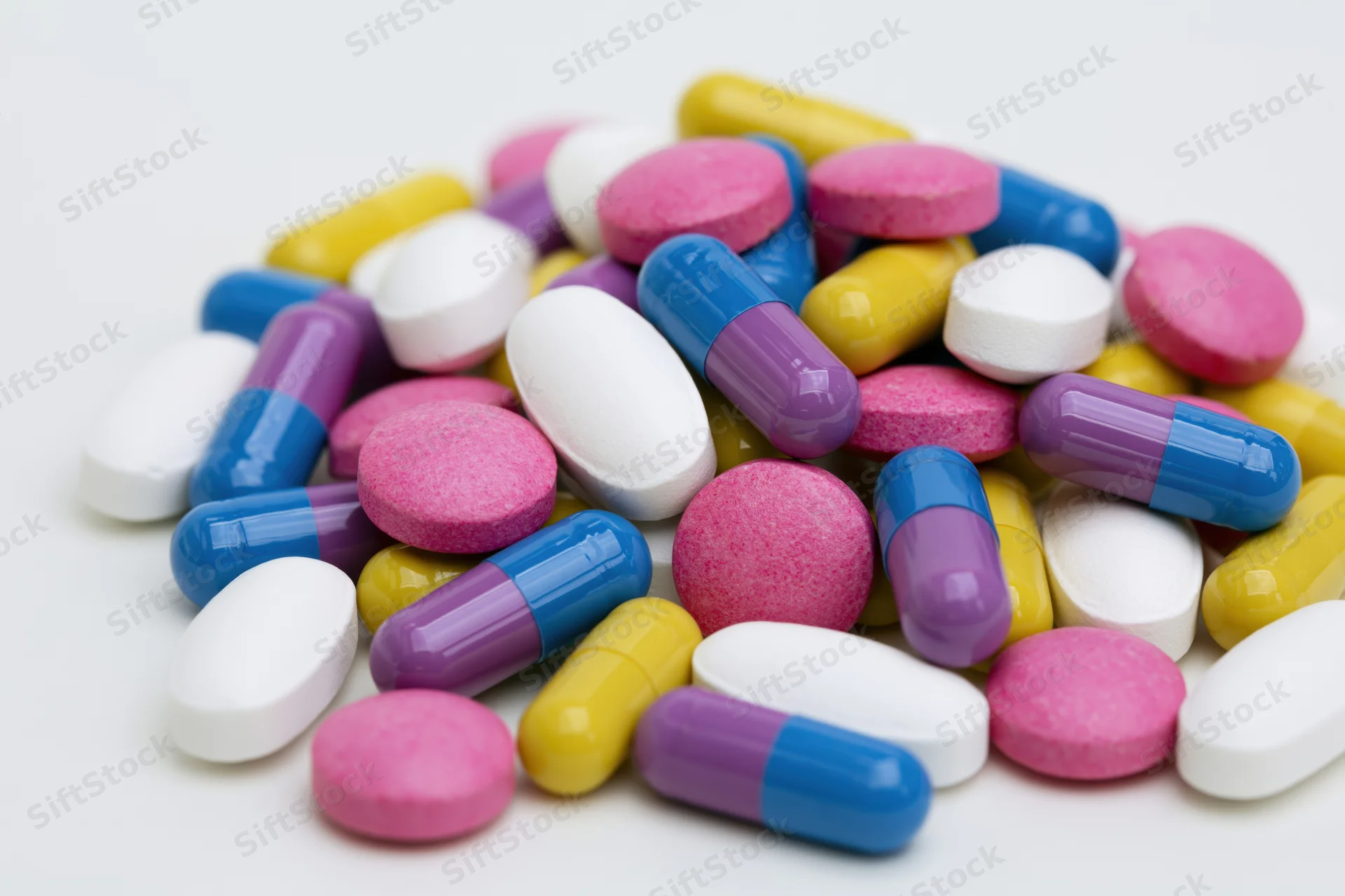 Scattered prescription pills and capsules on white background