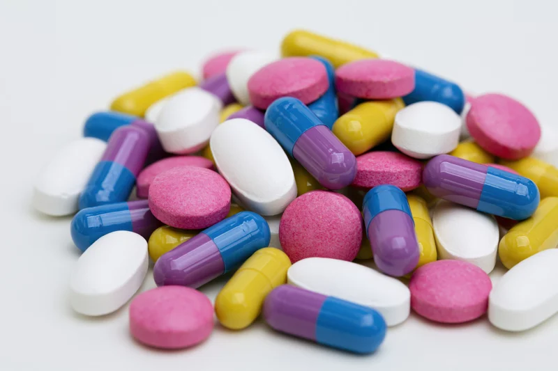 Scattered prescription pills and capsules on white background