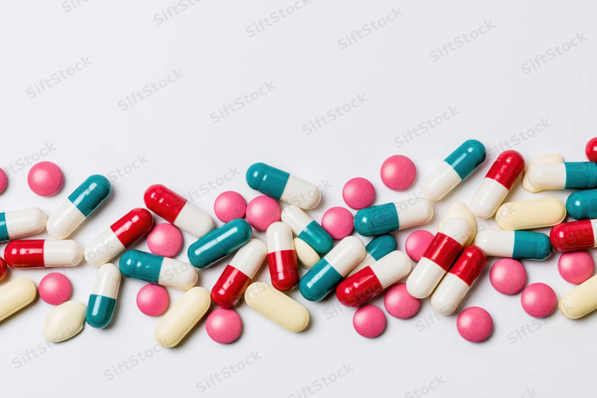 Scattered pharmaceutical pills and capsules on white background