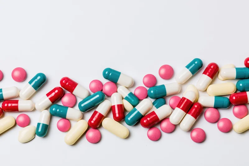 Scattered pharmaceutical pills and capsules on white background