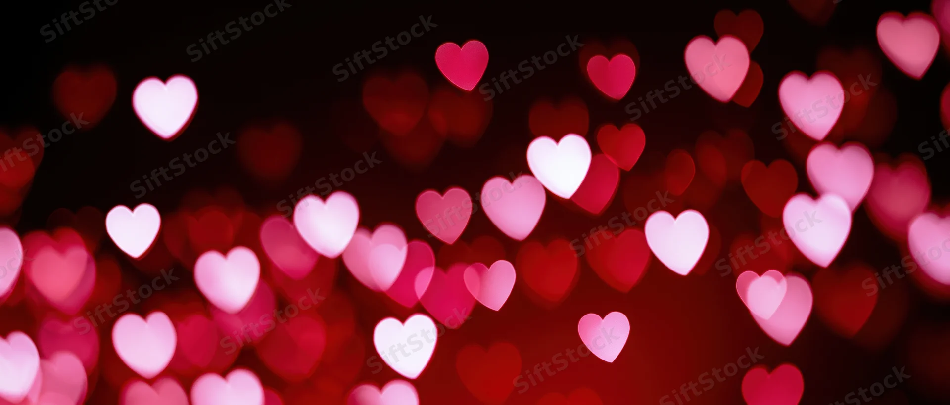 Scattered heart-shaped bokeh lights in red and pink tones against a dark background