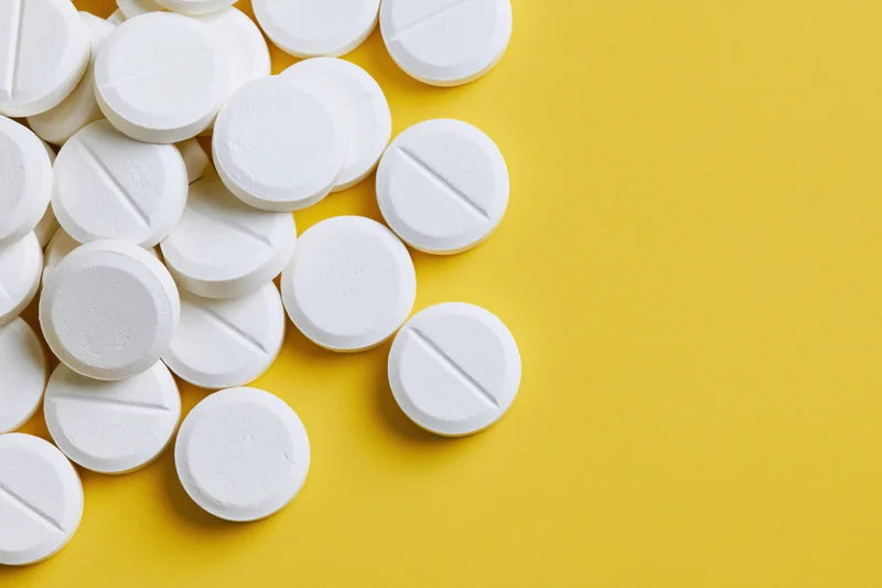 White round tablets scattered on a yellow surface with copyspace