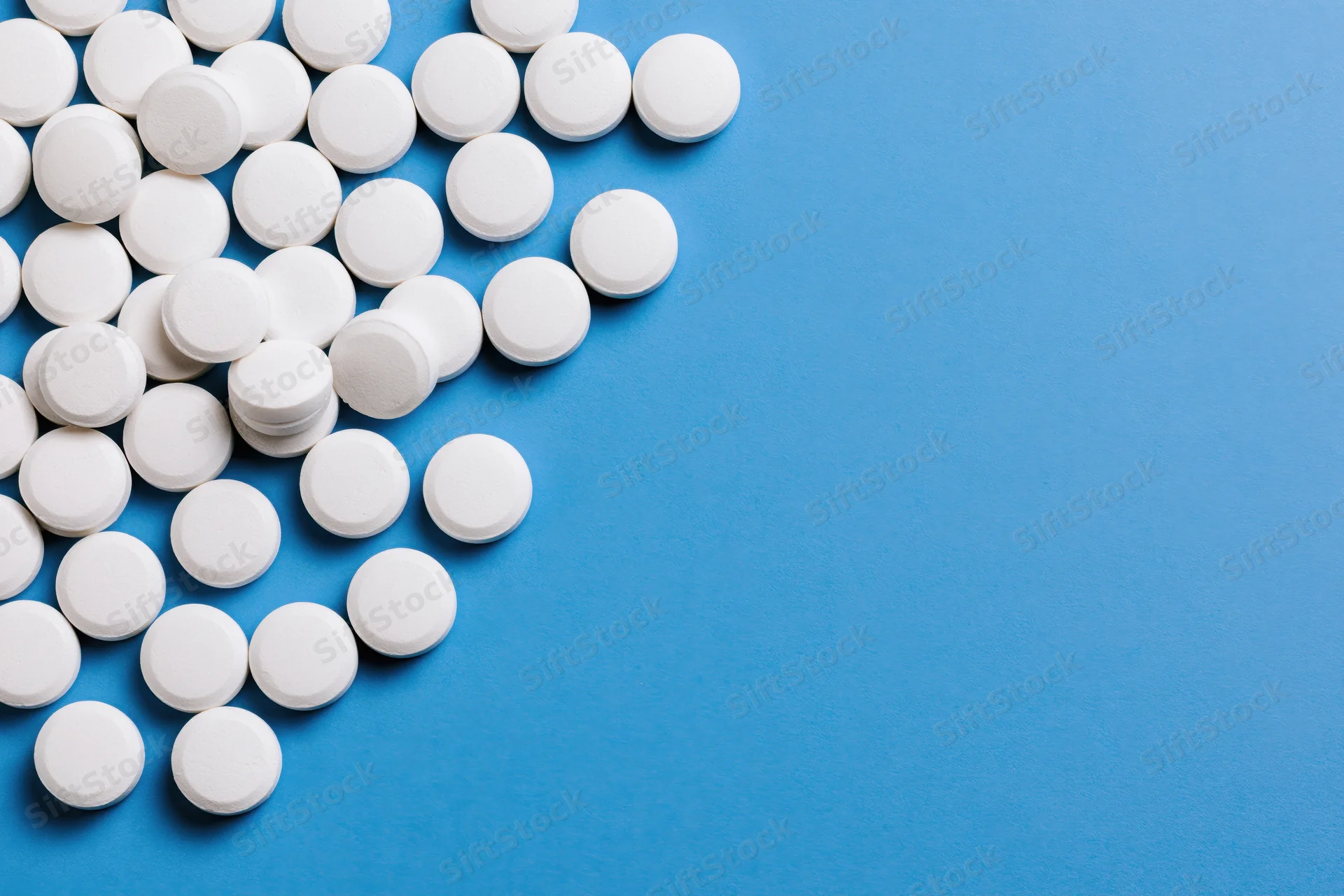 White round pills scattered on a bright blue surface