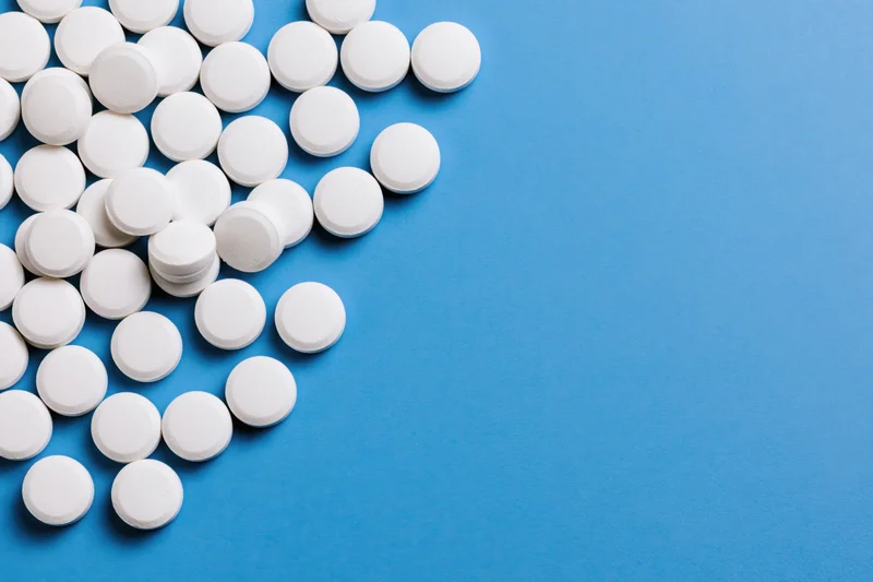 White round pills scattered on a bright blue surface