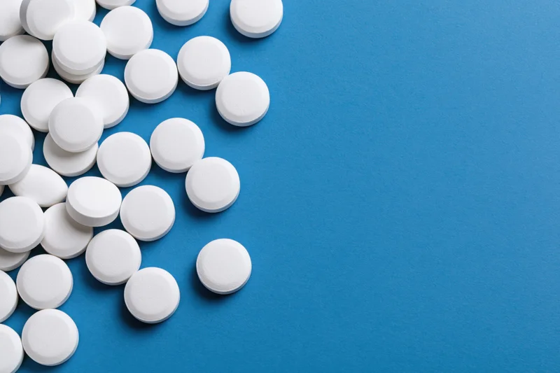 White round pills scattered on a bright blue surface
