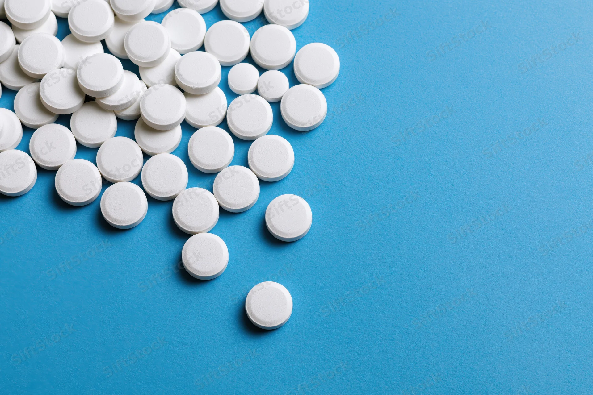 White round pills scattered across a bright blue surface