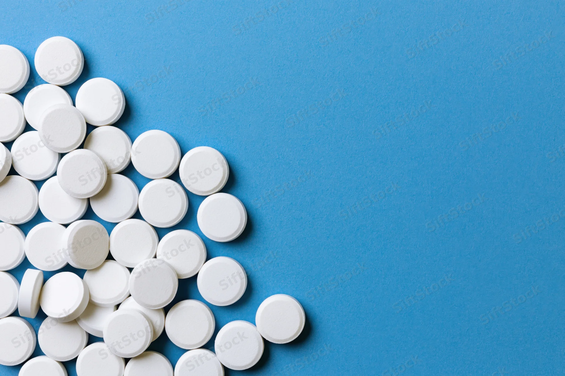 White round pills scattered on a bright blue surface