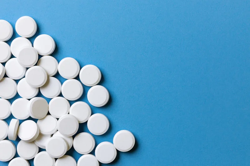 White round pills scattered on a bright blue surface
