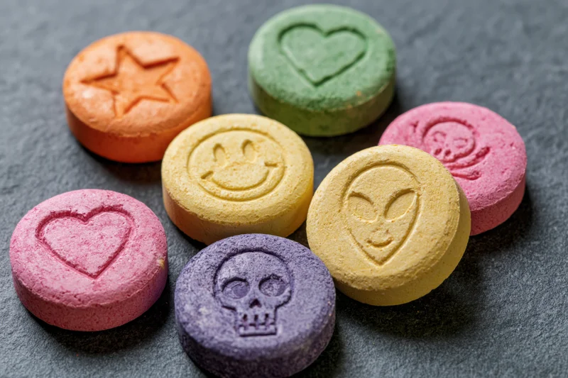 Colorful pressed tablets with symbols arranged on dark surface