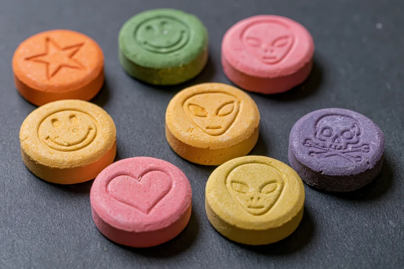 Colorful pressed tablets with various symbols arranged on dark surface