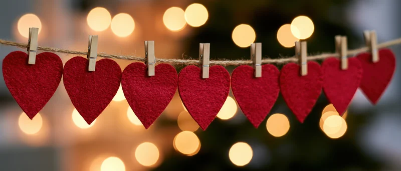 Red felt hearts clipped on a string with wooden clothespins against warm bokeh lights