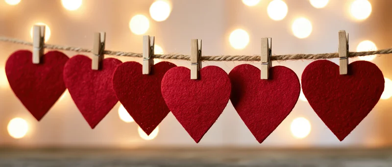 Red felt hearts clipped on a string with wooden clothespins against warm bokeh lights