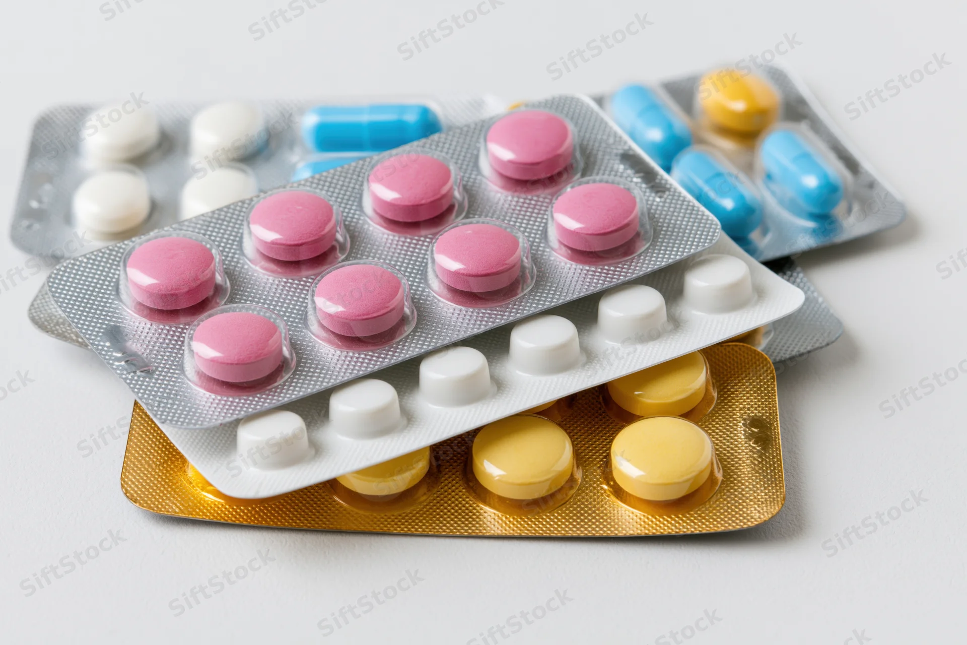 Several medication blister packs stacked loosely together on a white surface