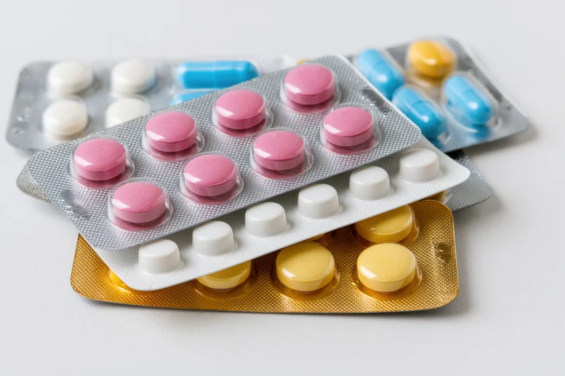 Several medication blister packs stacked loosely together on a white surface