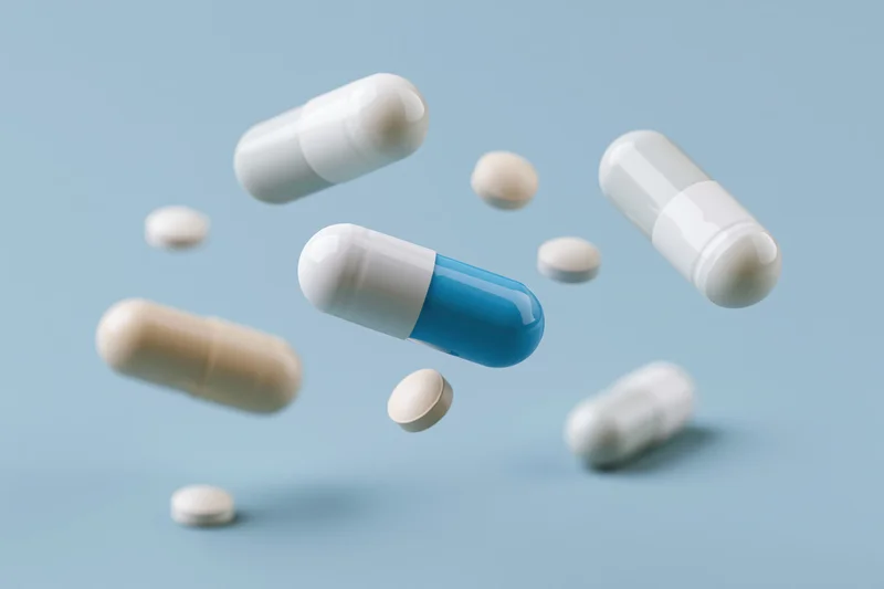 Floating pharmaceutical capsules and pills suspended in light blue space