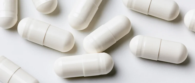 White pharmaceutical capsules scattered on a plain surface