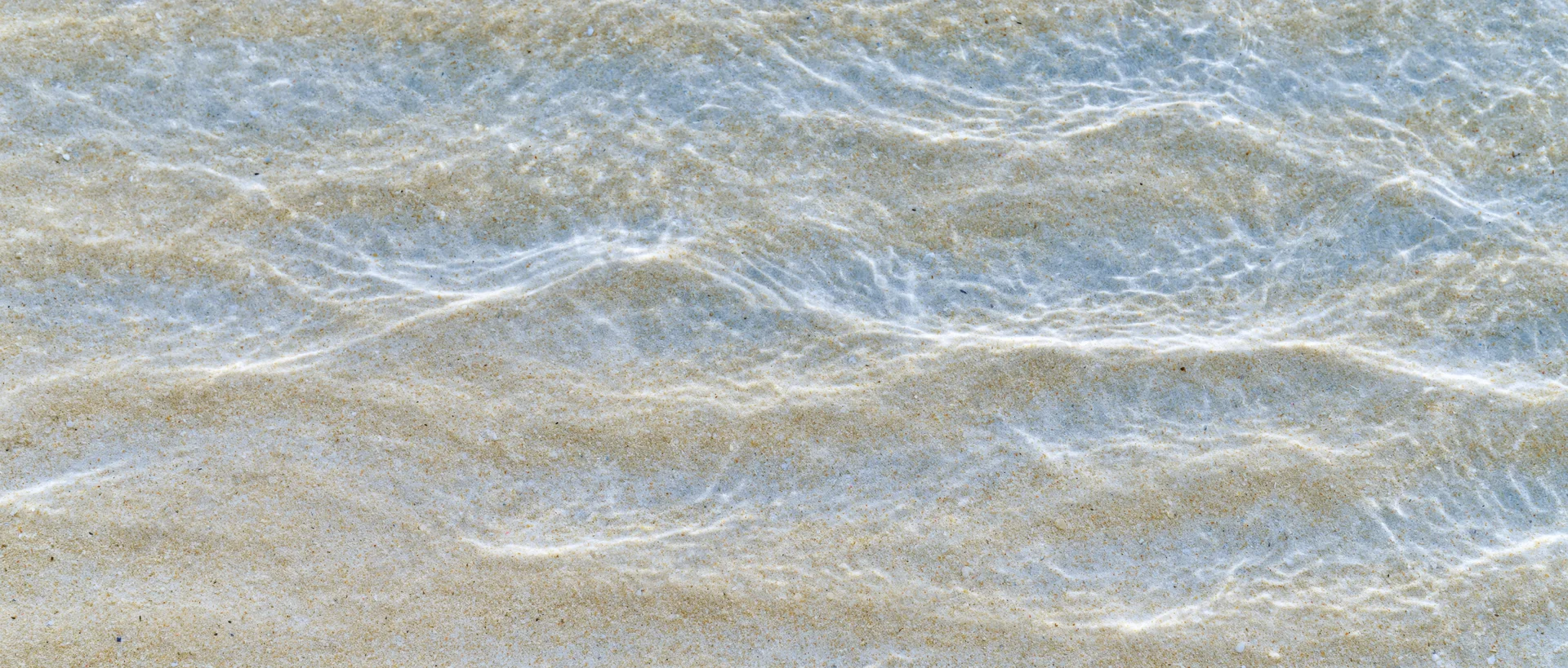 Shallow clear ocean water rippling over sandy seafloor