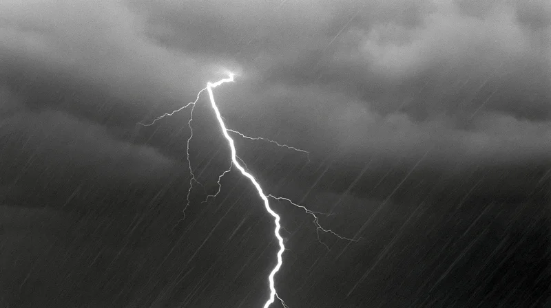 Lightning bolt striking downward through heavy rainfall in a stormy sky