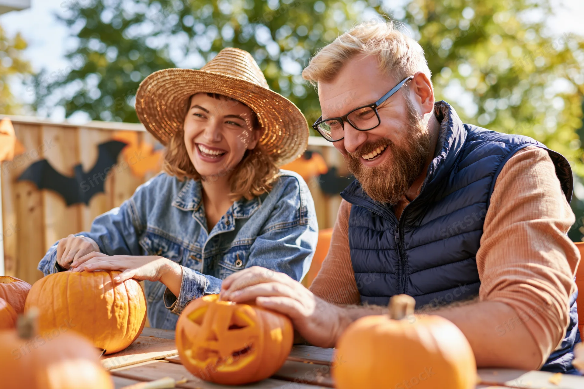 Couple carving pumpkins together outdoors on a sunny day