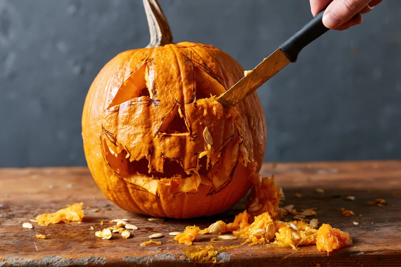 Hand carving a pumpkin with a knife on a wooden table