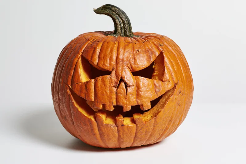 Carved pumpkin with angular face and grin on white background