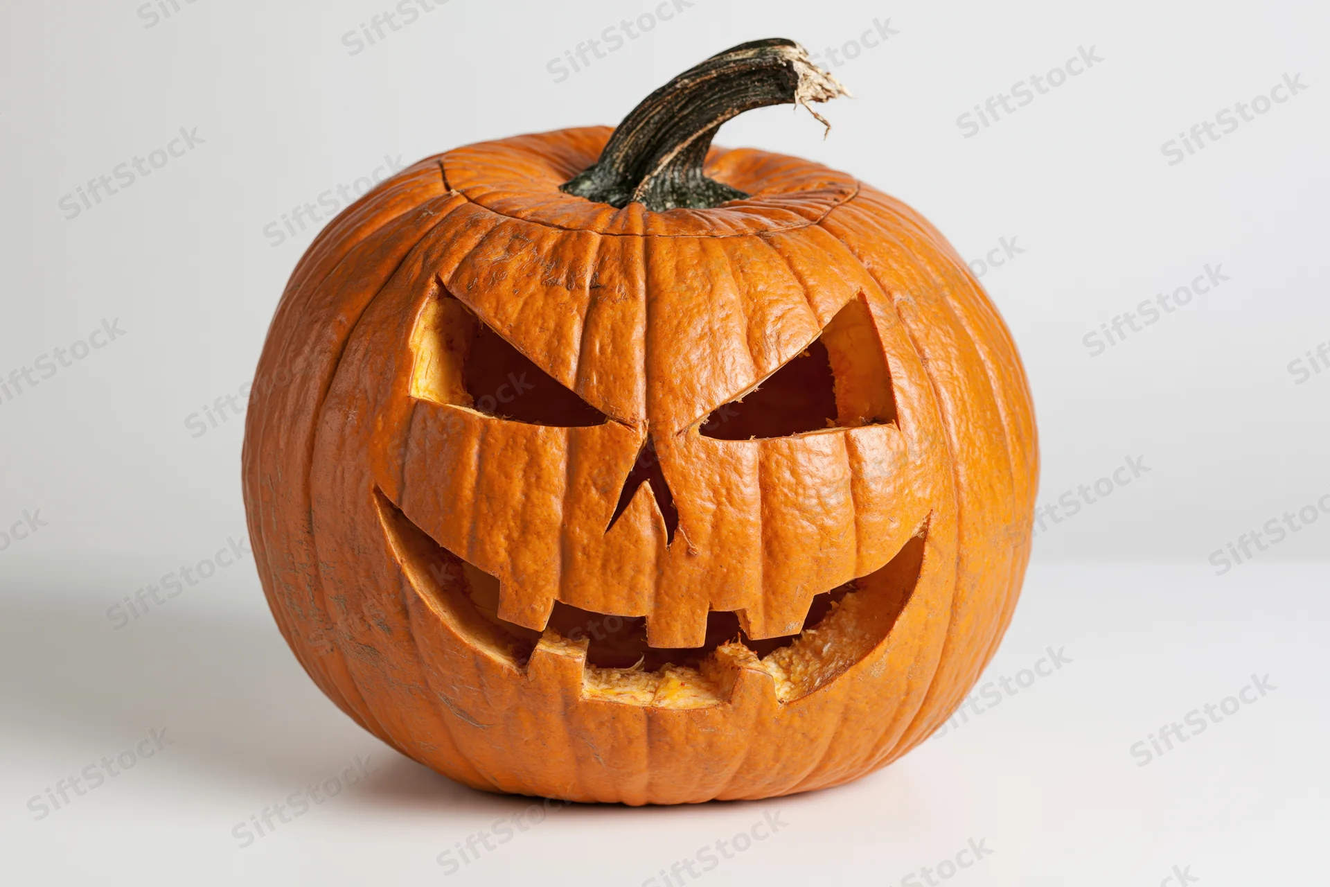 Carved pumpkin with angular face on white background
