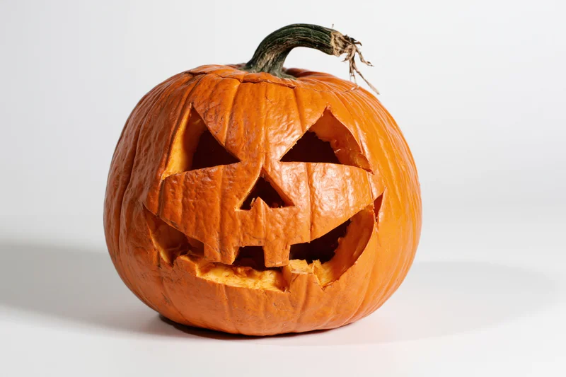 Carved pumpkin with angular face and stem on white background