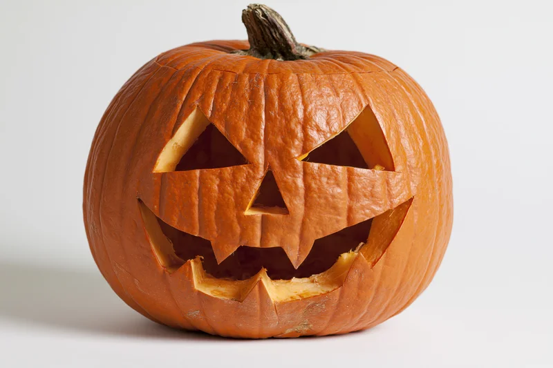 Carved pumpkin with angular eyes and jagged mouth on white background