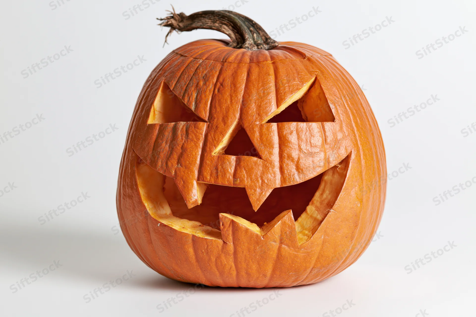 Carved pumpkin with angular eyes and jagged mouth on white background