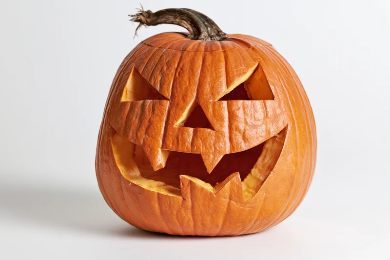 Carved pumpkin with angular eyes and jagged mouth on white background
