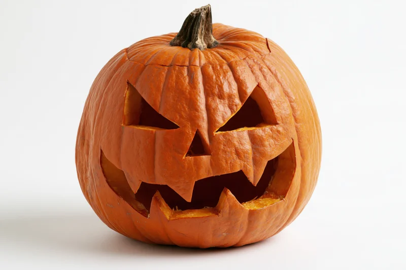 Carved pumpkin with angular eyes and jagged grin on white background