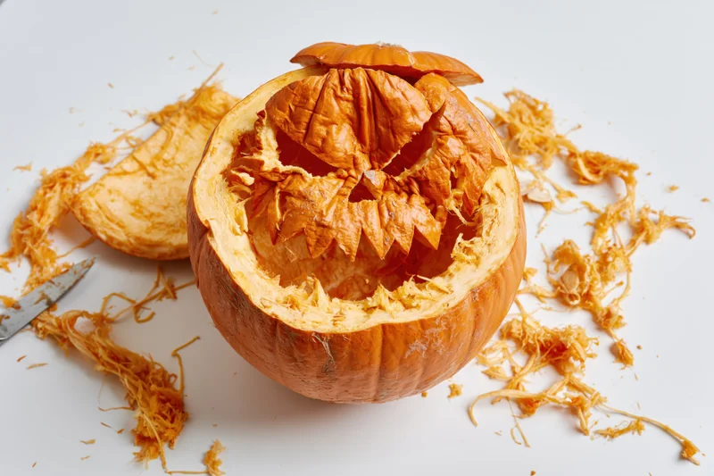 Carved pumpkin with jagged menacing face on white background
