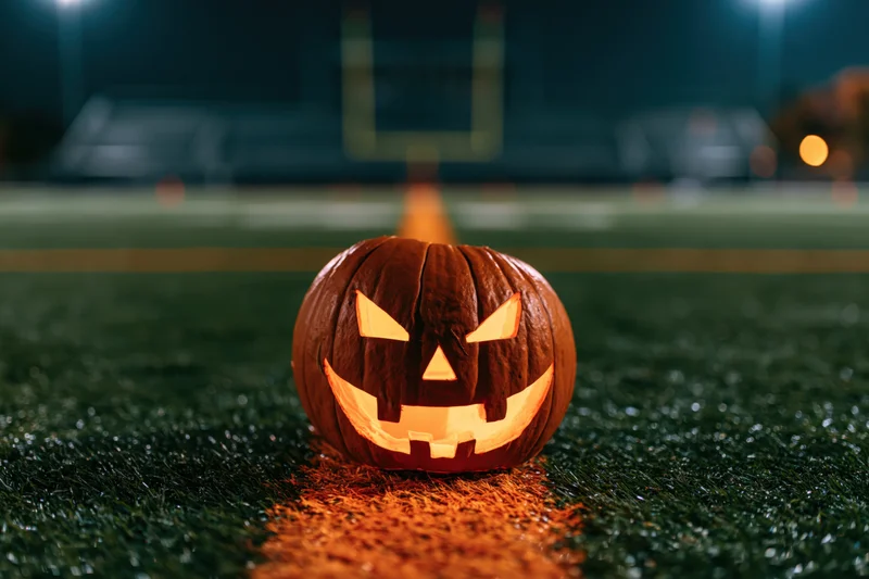 Carved jack-o-lantern glowing on football field at night