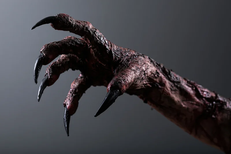 Clawed monster hand reaching forward against dark background