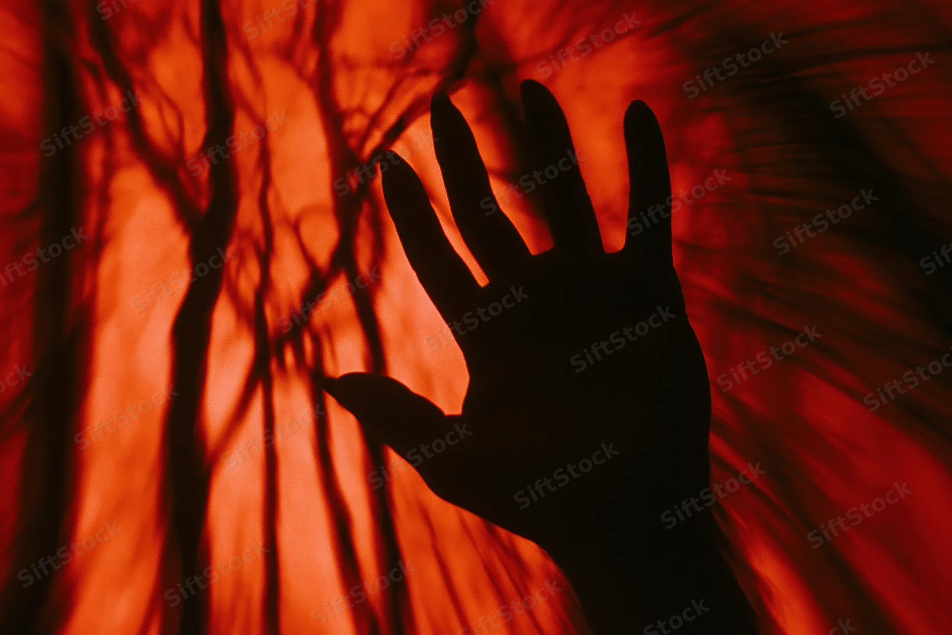 Silhouetted hand reaching upward with fingers spread against a red glowing background