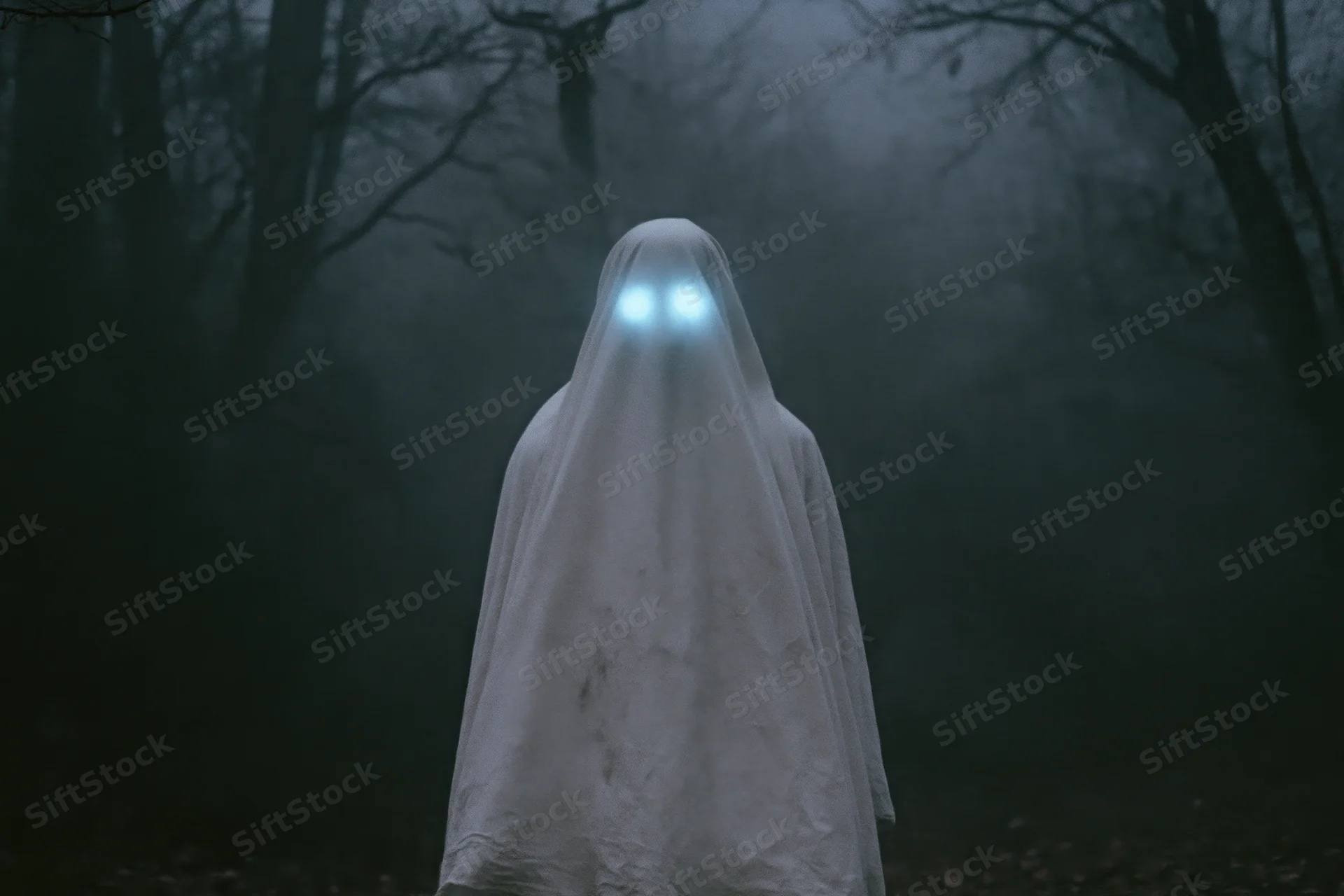 Ghostly figure in white sheet with glowing blue eyes standing in foggy forest at night