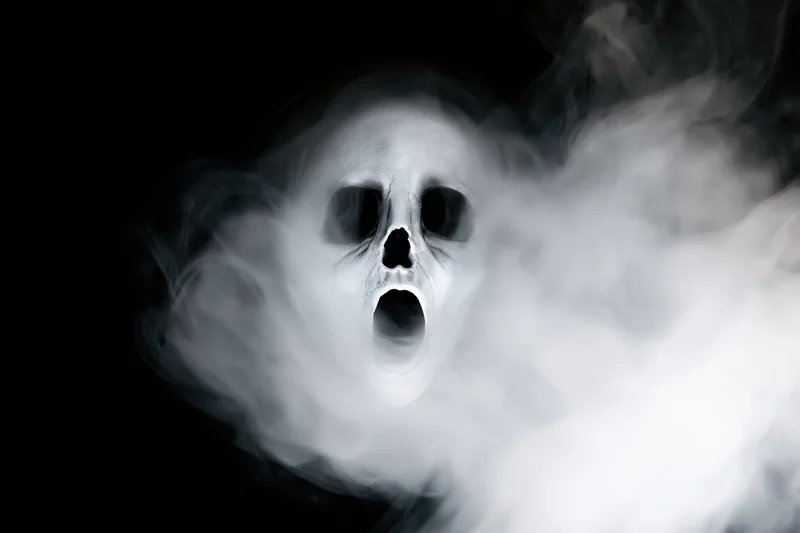 Ghostly skull screaming amidst swirling white smoke against black background