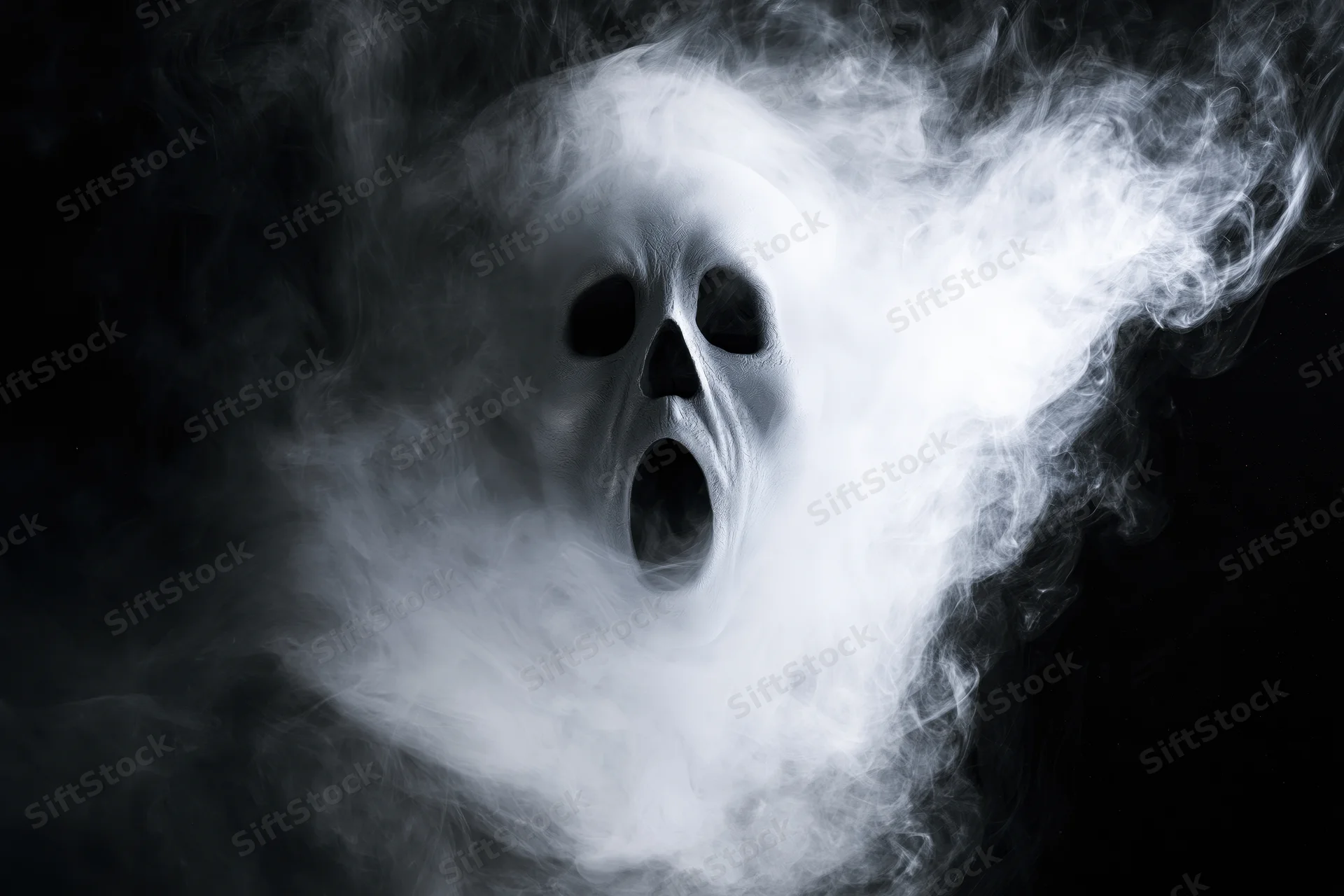 Ghostly screaming face emerging from swirling white smoke against black background
