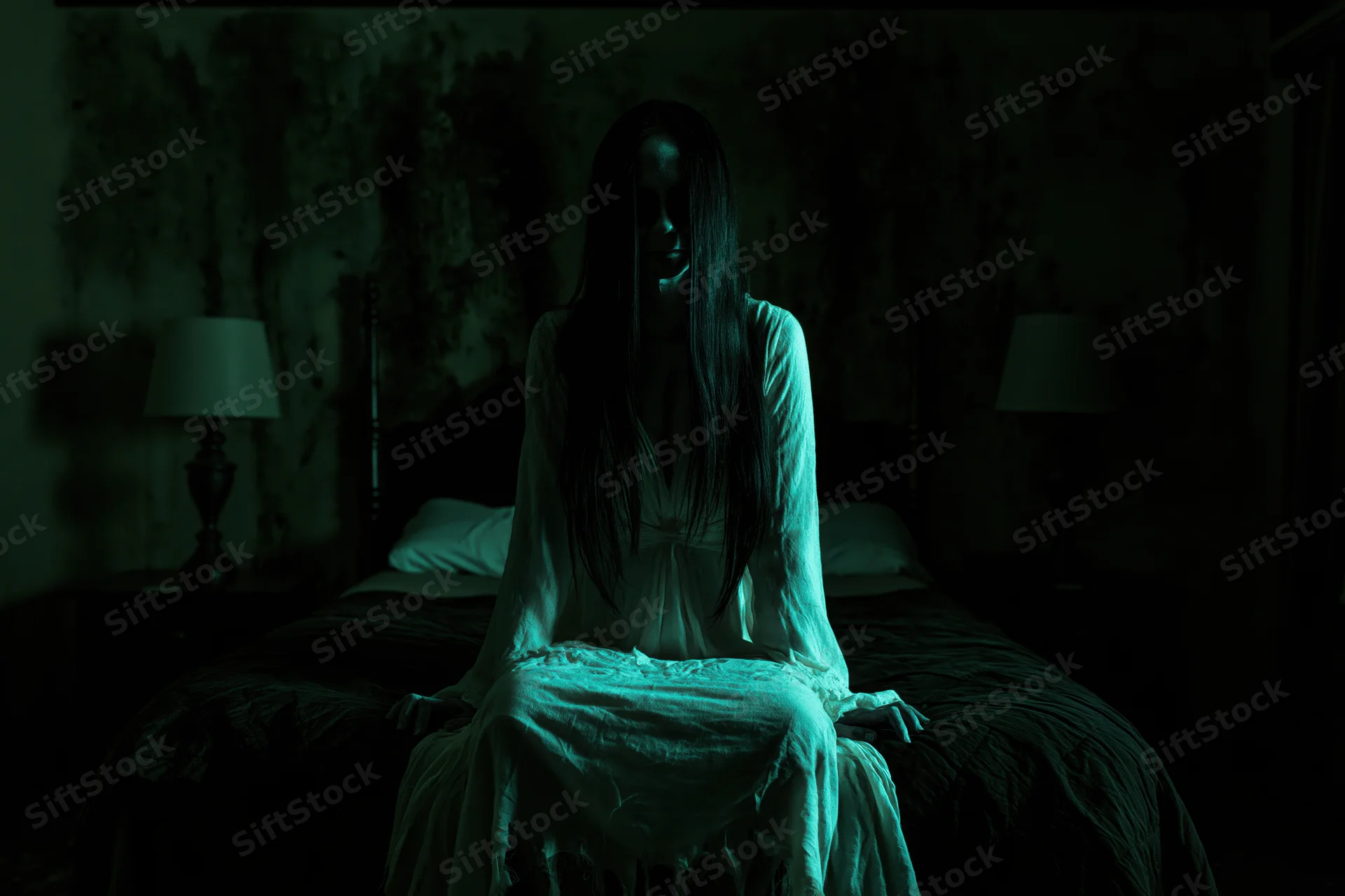 Ghostly woman in white gown sitting on bed in dark bedroom with green light