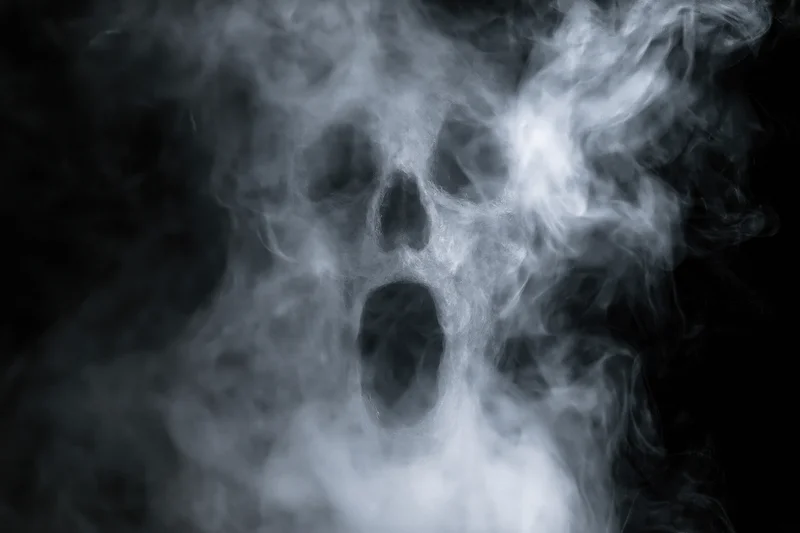 Ghostly screaming skull formed from swirling white smoke against black background